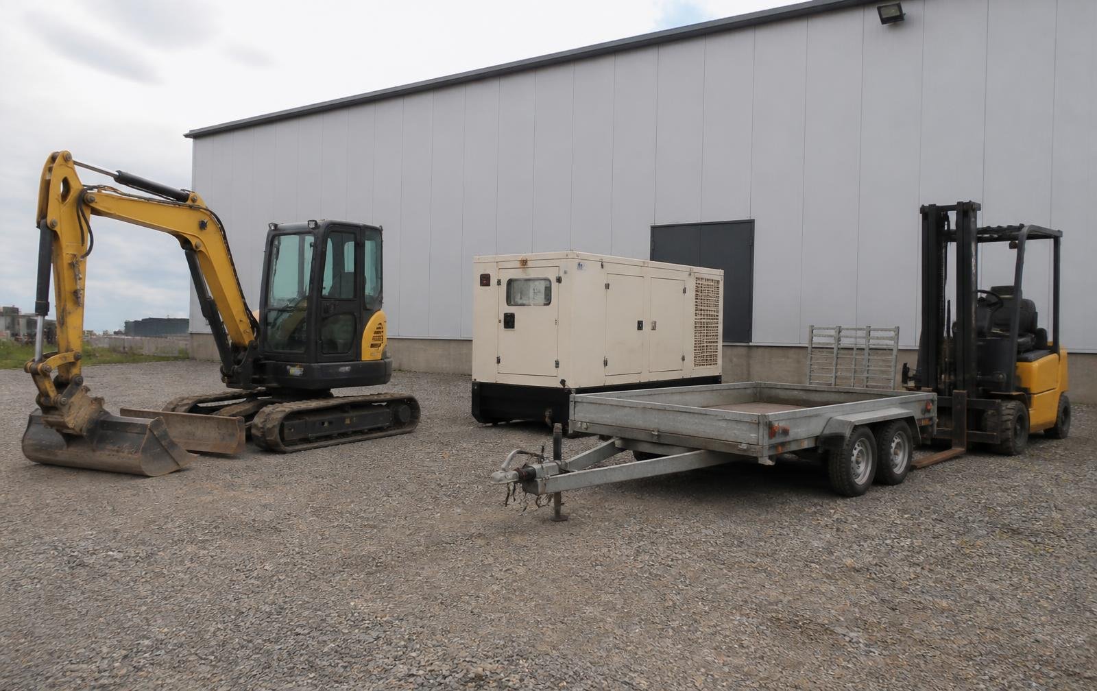 Excavator, generator, trailer and forklift parked at an industrial yard